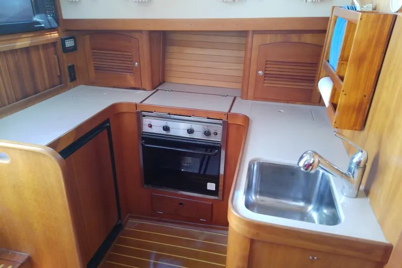 Slide: The Image of 2002 Sabreline 36 Express yacht kitchen with stove, sink, and wooden cabinetry. - 53
