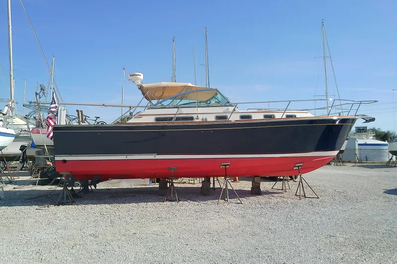 The Image of 2002 Sabreline 36 Express boat on stands, blue hull, red bottom, outdoor storage. - 0