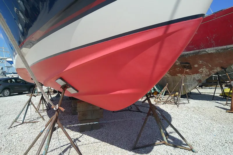 Slide: The Image of 2002 Sabreline 36 Express boat on stands, vibrant red hull, outdoor storage. - 42