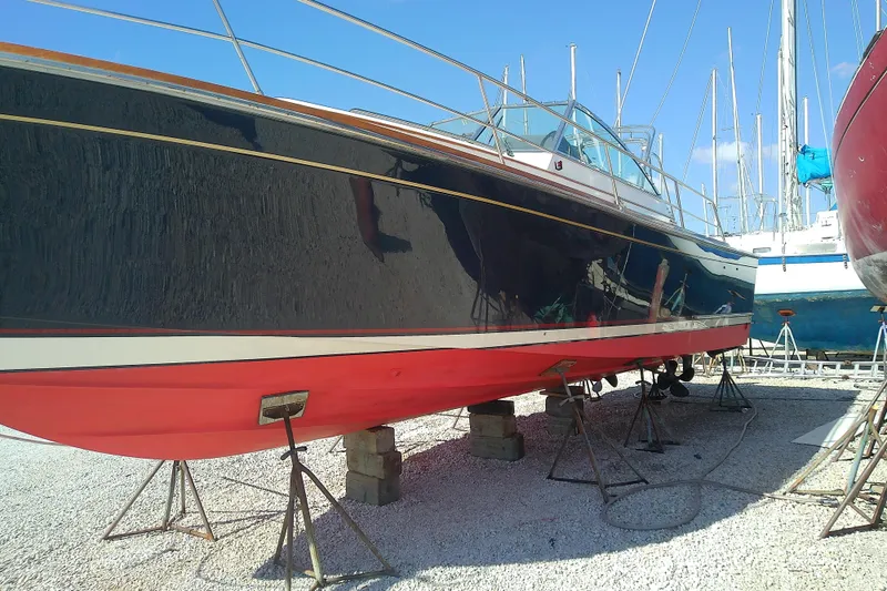 Slide: The Image of 2002 Sabreline 36 Express boat on stands, blue hull, red bottom, marina setting. - 50