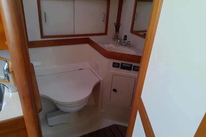 Slide: The Image of 2002 Sabreline 36 Express yacht bathroom with sink, toilet, and wooden accents. - 77