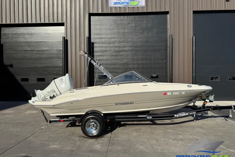 Slide: The Image of 2022 Stingray 191 DC boat on trailer, parked outside a building. - 0