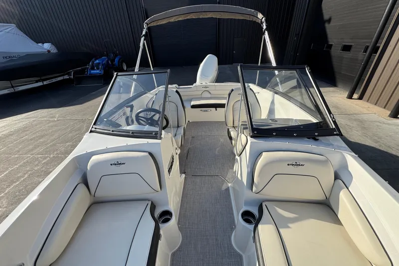 Slide: The Image of 2022 Stingray 191 DC boat interior with seating and steering wheel, docked outdoors. - 10