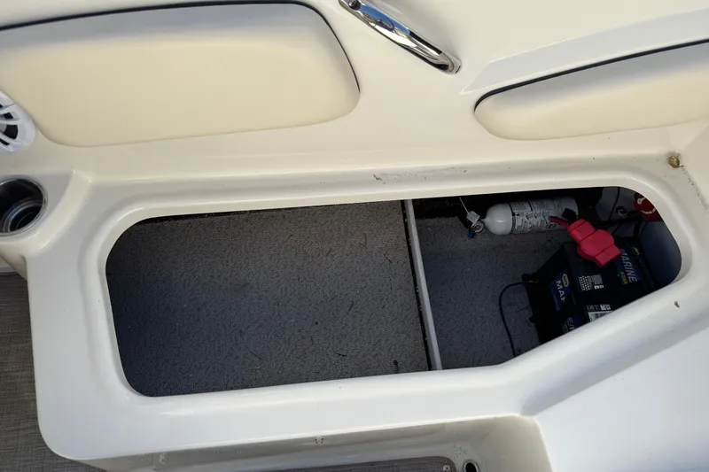Slide: The Image of Storage compartment in a 2022 Stingray 191 DC boat, featuring a battery and fire extinguisher. - 21