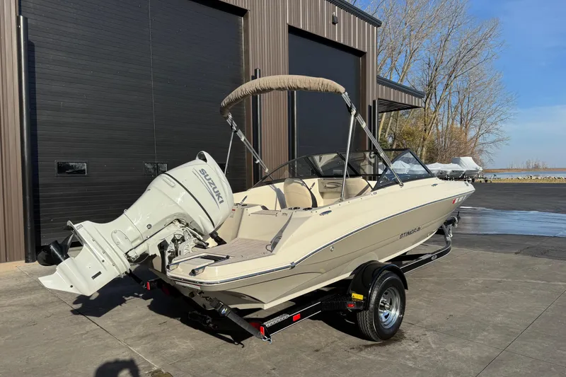 Slide: The Image of 2022 Stingray 191 DC boat with Suzuki outboard motor on trailer, parked outdoors. - 4