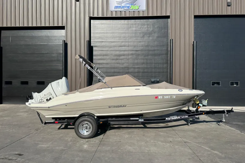 Slide: The Image of 2022 Stingray 191 DC boat on trailer, parked outside a garage. - 6