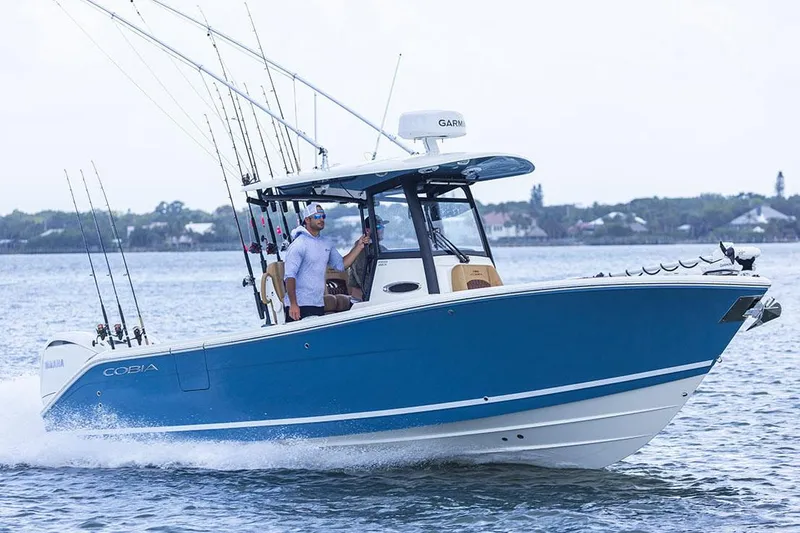 Slide: The Image of Manufacturer Provided Image: 2025 Cobia 265 Center Console Open boat cruising on water with fishing rods. - 1