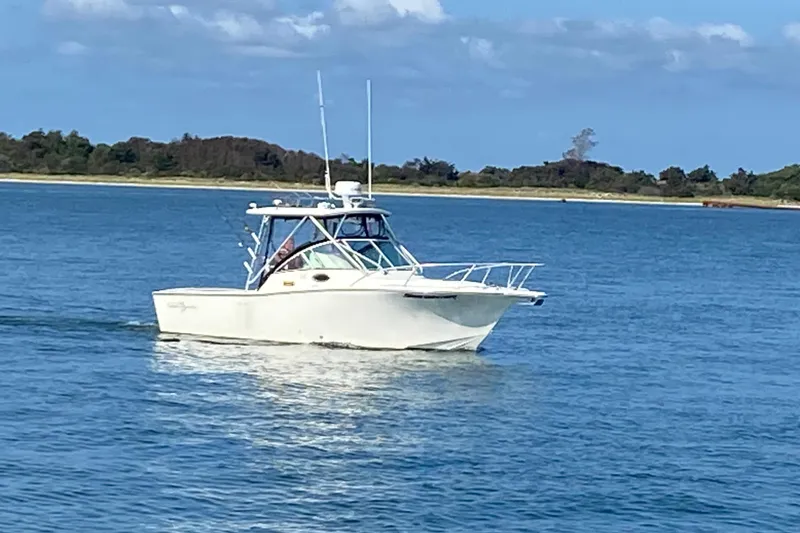 Slide: The Image of 2006 Albemarle 268 Express Fisherman boat cruising on blue water near a scenic shoreline. - 7