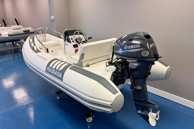 Slide: The Image of 2025 Novurania DL 335 boat with Yamaha 25 HP engine displayed indoors. - 2
