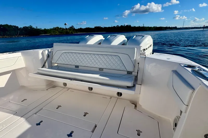 Slide: The Image of 2020 Intrepid 375 Nomad SE boat interior with seating and triple engines on a sunny day. - 18