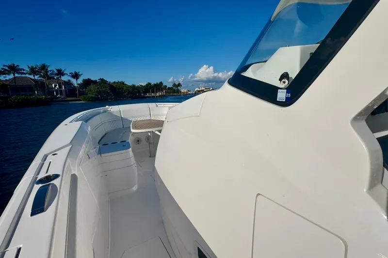 Slide: The Image of 2020 Intrepid 375 Nomad SE boat on calm water, clear sky, and lush shoreline. - 28