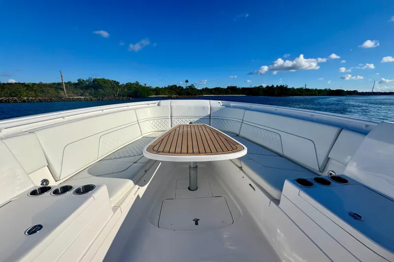 Slide: The Image of 2020 Intrepid 375 Nomad SE boat interior with wooden table, cup holders, and scenic water view. - 31
