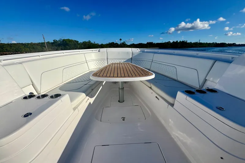 Slide: The Image of 2020 Intrepid 375 Nomad SE boat interior with seating and table, under clear blue sky. - 32