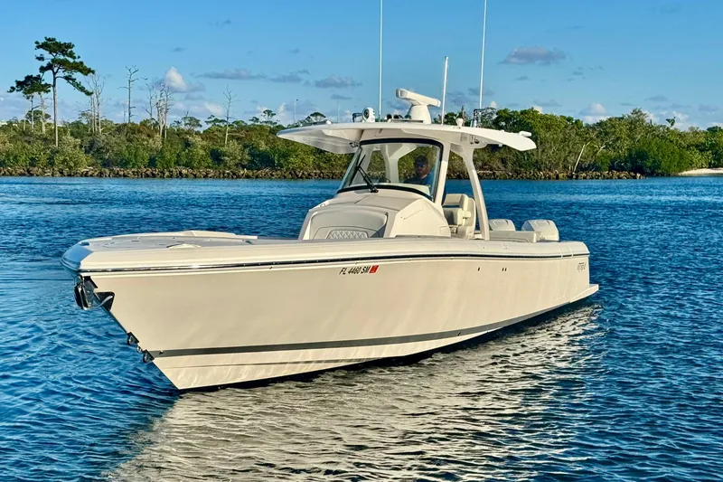 Slide: The Image of 2020 Intrepid 375 Nomad SE boat on calm water, surrounded by lush greenery. - 6