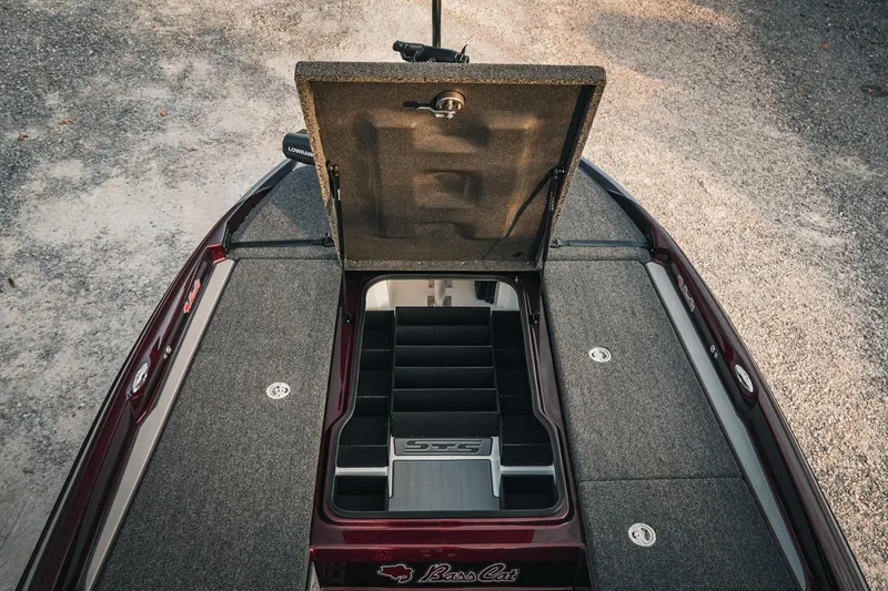 Slide: The Image of 2026 Bass Cat Lynx STS boat with open storage compartment, gray carpeted deck. - 20