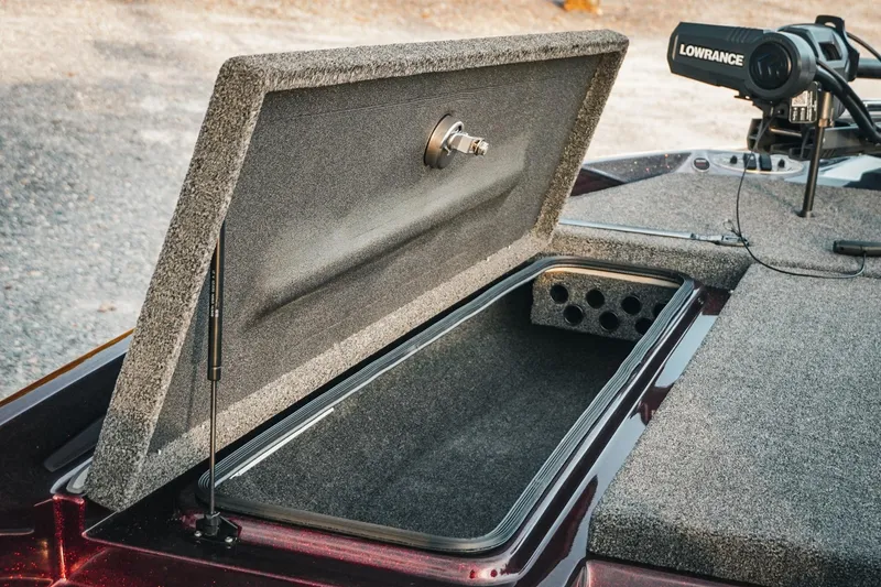 Slide: The Image of 2026 Bass Cat Lynx STS boat storage compartment with open lid and Lowrance equipment. - 24