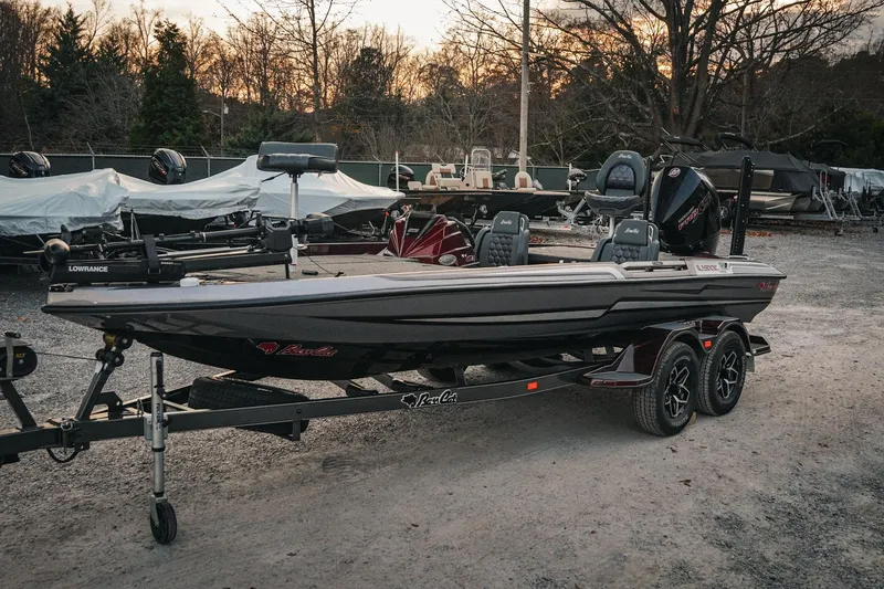 Slide: The Image of 2026 Bass Cat Lynx STS boat on trailer, parked outdoors at sunset. - 31
