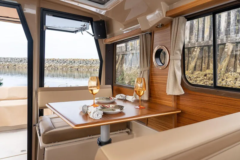 Slide: The Image of Manufacturer Provided Image: Interior of 2025 Ranger Tugs R-23 boat with dining table and scenic window view. - 11