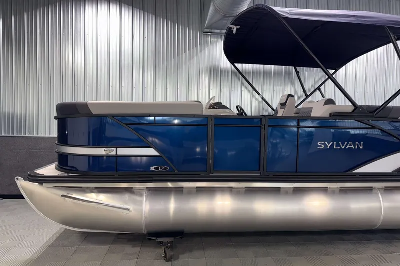 Slide: The Image of 2026 Sylvan L3 SLZ pontoon boat with blue exterior and canopy in showroom. - 29