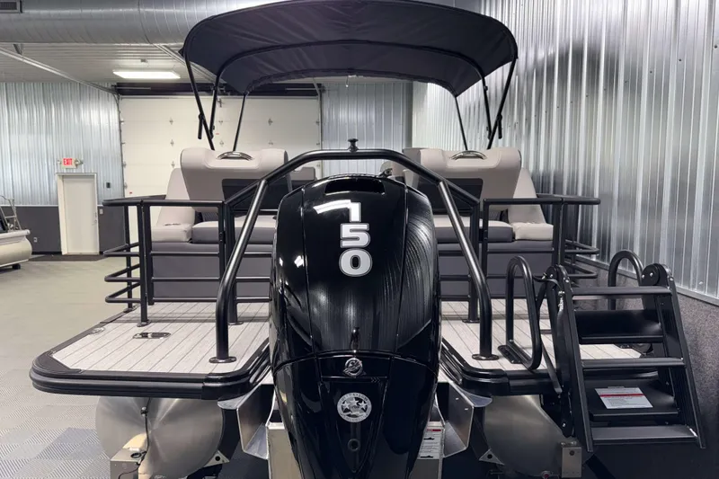 Slide: The Image of 2026 Sylvan L3 SLZ pontoon boat with black motor in a metal-walled showroom. - 33