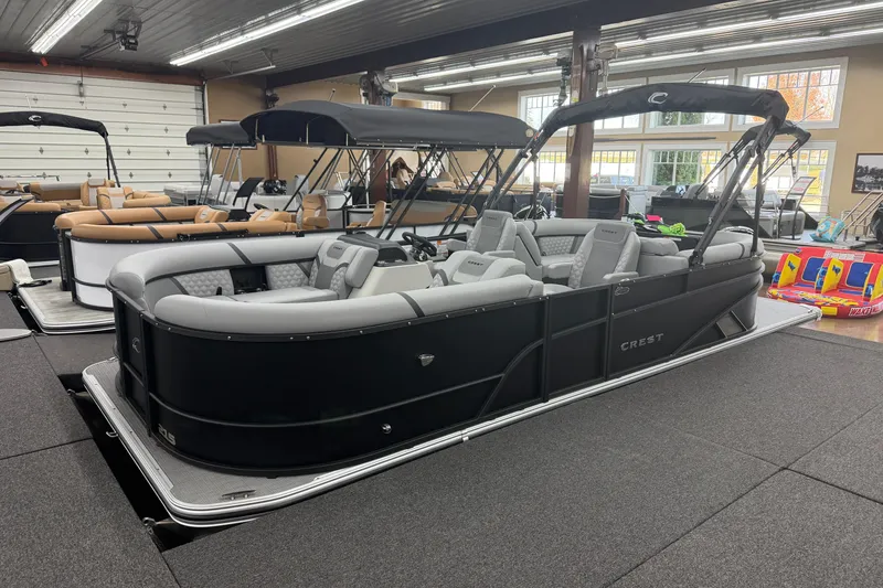 The Image of 2026 Crest Conquest 215 SLC pontoon boat in showroom, featuring sleek black design and spacious seating. - 0