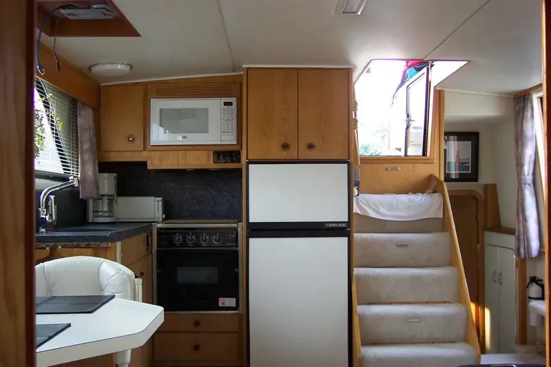 Slide: The Image of 1989 Chris-Craft 381 Catalina interior with kitchen, stairs, and dining area. - 13