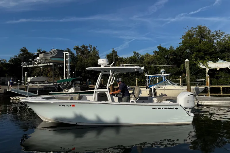 Slide: The Image of 2021 Sportsman Open 242 Center Console boat docked at marina under clear blue sky. - 10
