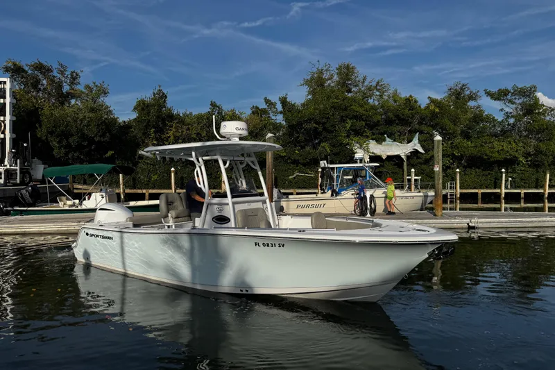 Slide: The Image of 2021 Sportsman Open 242 Center Console boat docked in a marina under clear skies. - 14