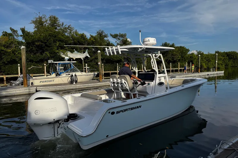 Slide: The Image of 2021 Sportsman Open 242 Center Console boat on water, Yamaha engine, docked near trees. - 17