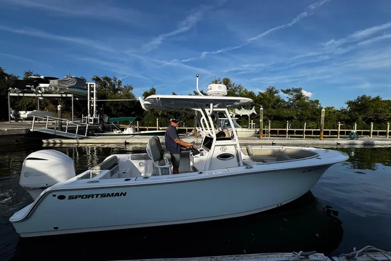 Slide: The Image of 2021 Sportsman Open 242 Center Console boat on calm water near a dock. - 19