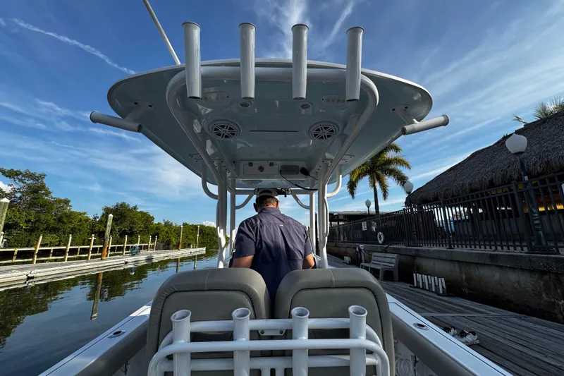 Slide: The Image of 2021 Sportsman Open 242 Center Console boat docked, viewed from the rear, under a clear sky. - 27