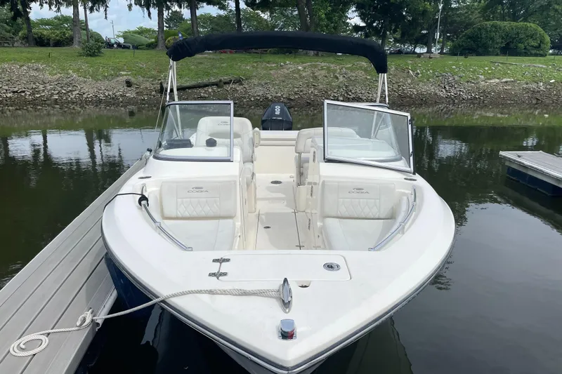 Slide: The Image of 2021 Cobia 220 Dual Console boat docked on calm water. - 2