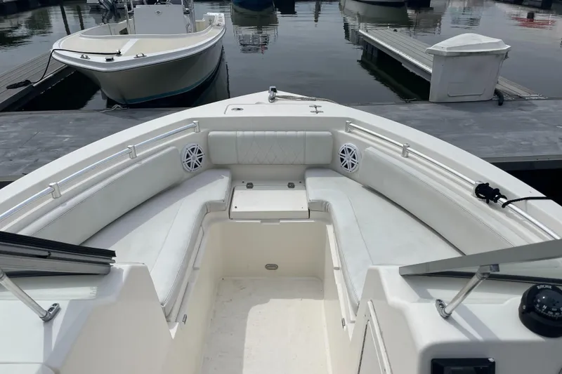 Slide: The Image of 2021 Cobia 220 Dual Console boat interior with white seating at a marina. - 4