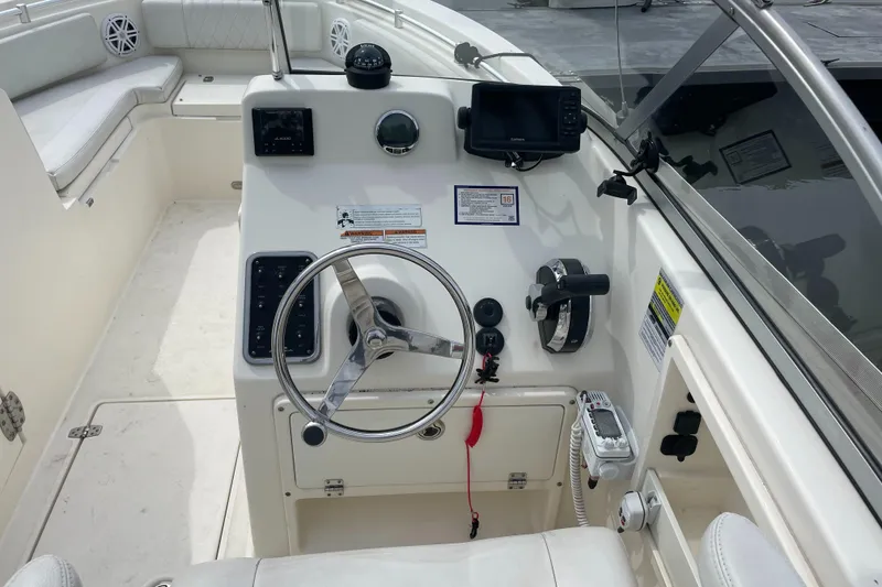 Slide: The Image of 2021 Cobia 220 Dual Console boat cockpit with steering wheel and control panel. - 6
