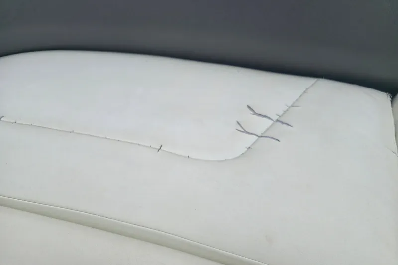 Slide: The Image of Damaged white upholstery on 2001 Cobalt 232 boat seat with visible stitching repair. - 17