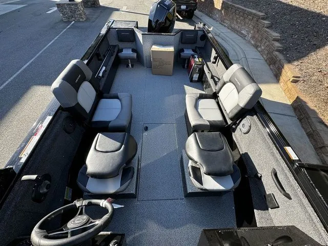 Slide: The Image of 2024 Crestliner 2050 Commander boat interior with seating and steering wheel, parked outdoors. - 11