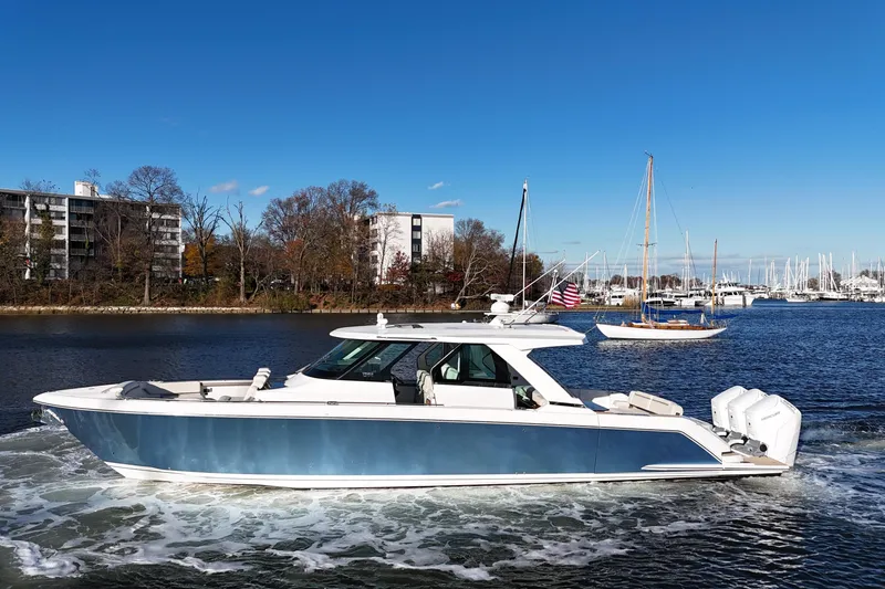 The Image of 2024 Tiara Yachts 48 LS cruising on a scenic waterway with clear blue skies. - 0