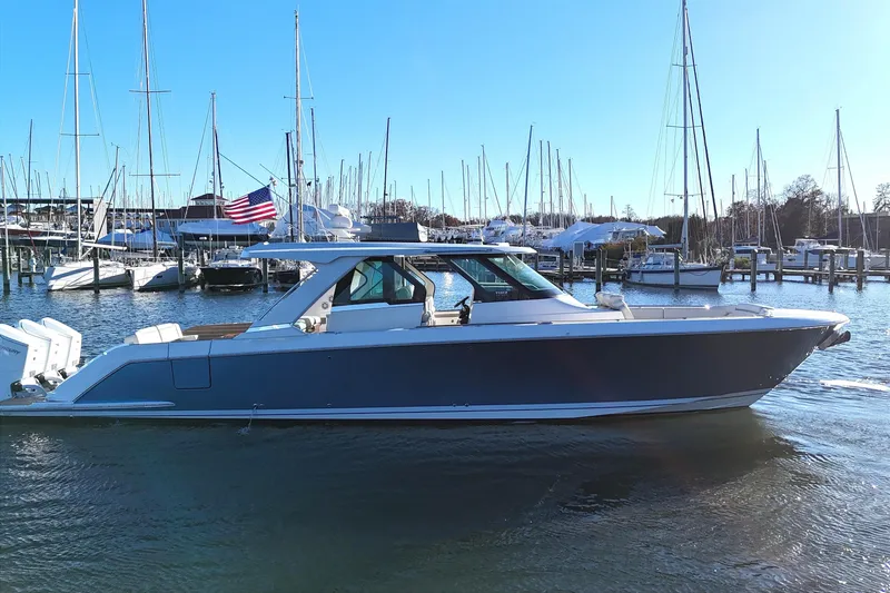 Slide: The Image of 2024 Tiara Yachts 48 LS in harbor, featuring American flag. - 2