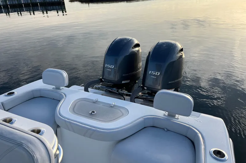 Slide: The Image of 2023 Contender 24 Sport boat with dual Yamaha 150 engines on calm water. - 2