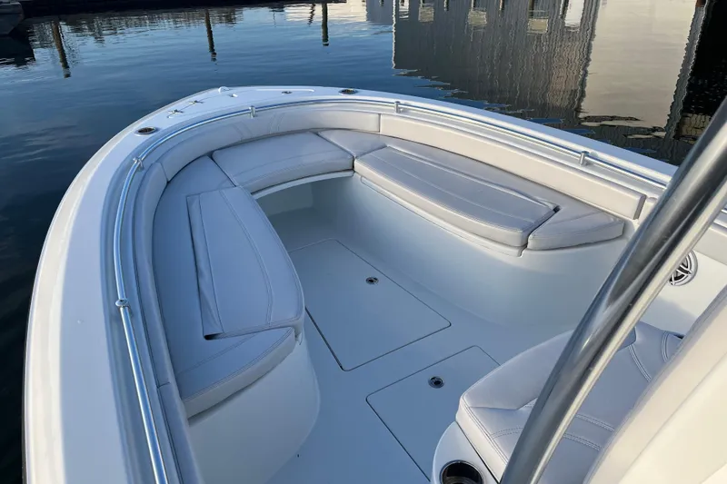Slide: The Image of 2023 Contender 24 Sport boat interior with cushioned seating, docked on calm water. - 21