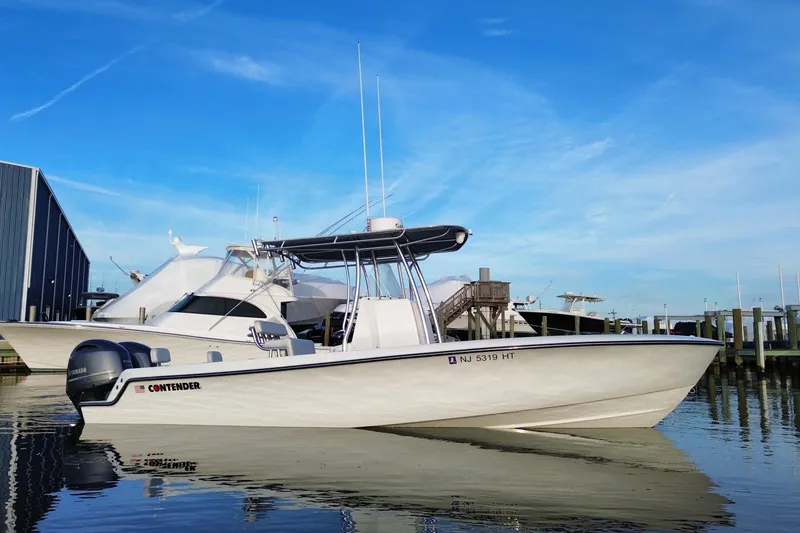 Slide: The Image of 2023 Contender 24 Sport boat docked at marina under clear blue sky. - 3