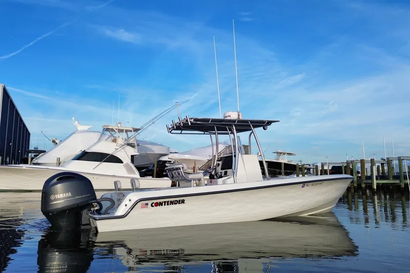 Slide: The Image of 2023 Contender 24 Sport boat docked with Yamaha engine, clear blue sky. - 4