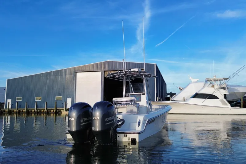 Slide: The Image of 2023 Contender 24 Sport boat with dual Yamaha engines near a marina. - 6