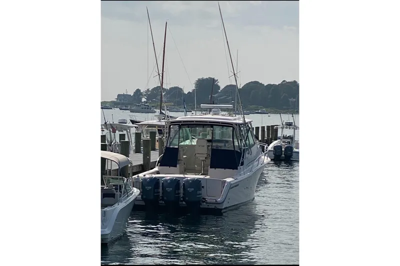 Slide: The Image of 2014 Grady-White Express 370 boat docked at a marina with triple outboard engines. - 2