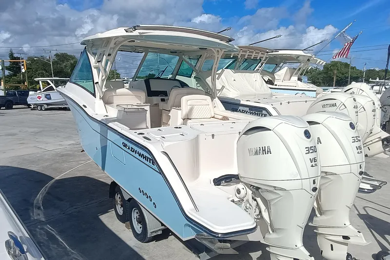 Slide: The Image of 2026 Grady-White Freedom 325 boat with twin Yamaha 350 engines, docked under blue sky. - 6