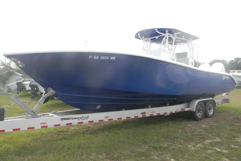 Slide: The Image of 2017 Yellowfin 32 Offshore boat on trailer, blue hull, parked on grass. - 3