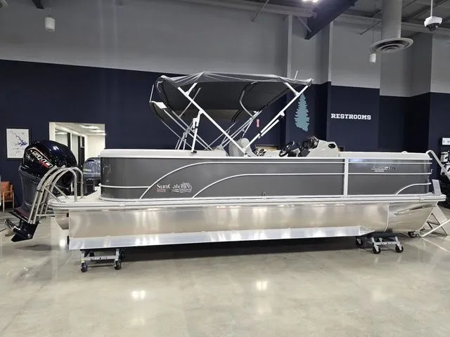 The Image of 2024 SunCatcher Select 322RC pontoon boat displayed indoors with canopy and outboard motor. - 1