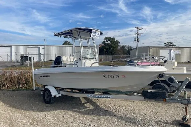 The Image of 2011 Triumph 190 Bay boat on trailer, parked outdoors under a clear sky. - 1