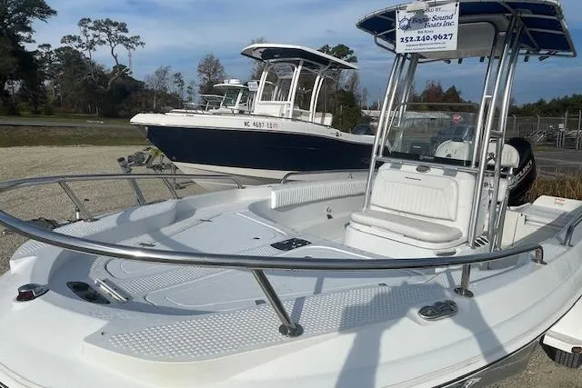 Slide: The Image of 2011 Triumph 190 Bay boat with T-top, parked outdoors, showcasing sleek design and spacious deck. - 17