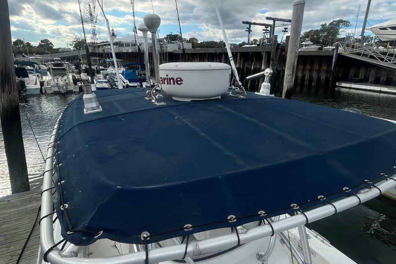 Slide: The Image of 2006 Boston Whaler 240 Outrage boat docked, featuring a blue canvas cover and marine equipment. - 23